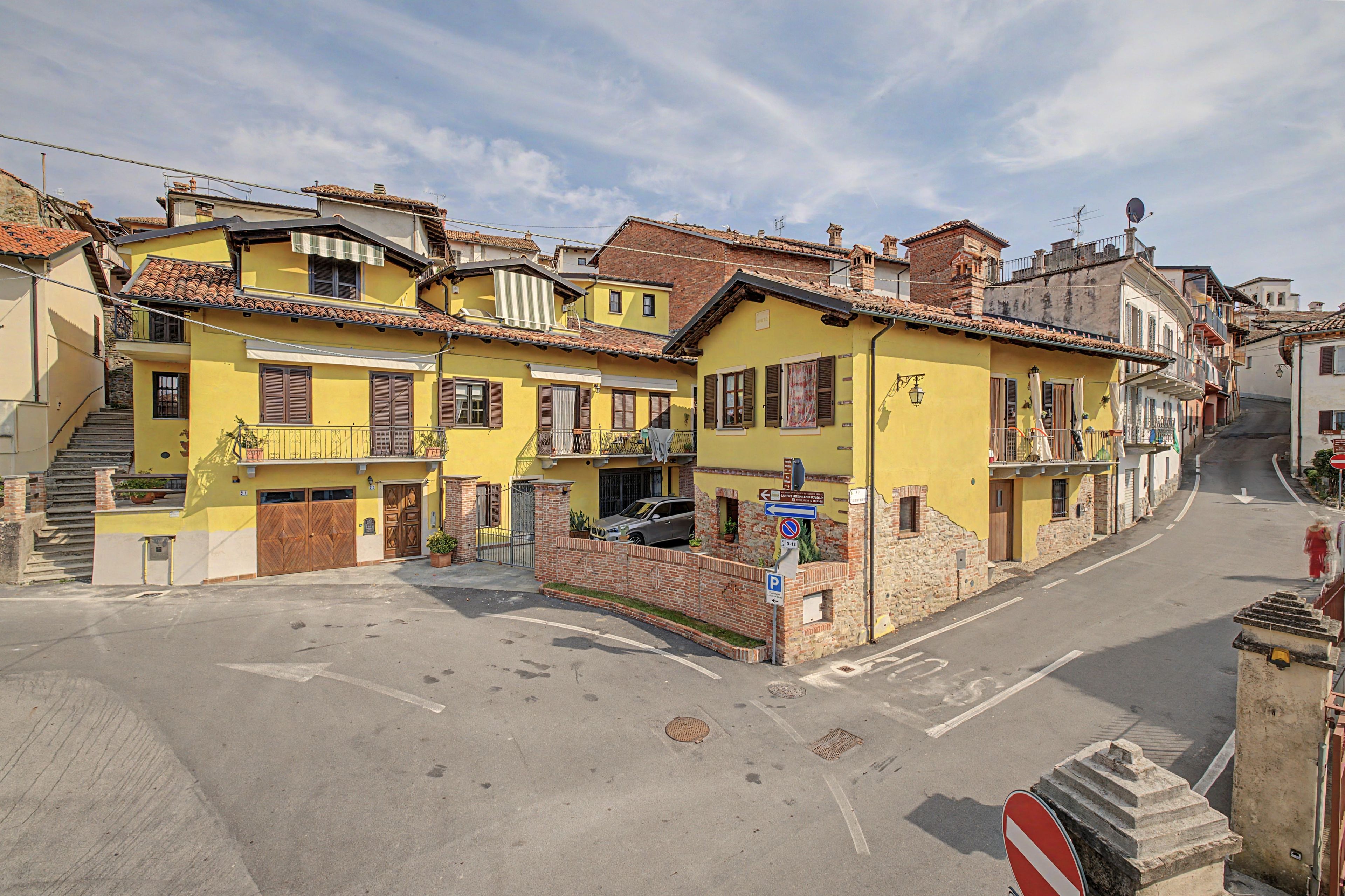 A street view with yellow buildings, a no entry sign, and a pedestrian.
