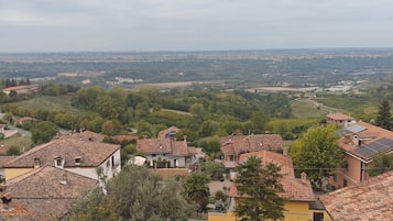 A residential area with terracotta-roofed houses, some with visible balconies, and a hilly landscape in the background.