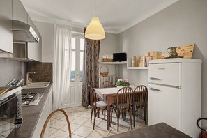 A modern kitchen with a dining area, a refrigerator, and a TV on the wall.