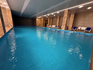 An indoor swimming pool with clear water, a tiled floor, and lounge chairs along the wall. - Studio 45 Apartment in Tsaghkadzor (Tsaghkadzor)