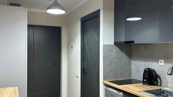 Une cuisine moderne avec une table en bois, des appareils électroménagers intégrés et des luminaires suspendus.