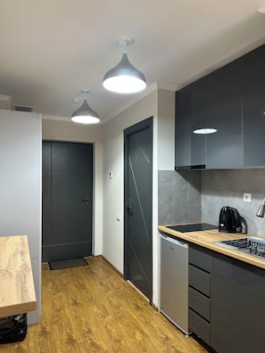 A modern kitchen with a wooden table, built-in appliances, and pendant lighting.