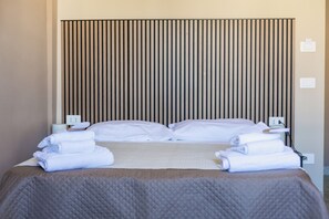 A hotel room with a bed, pillows, a blanket, and towels. There are two bedside tables with lamps and a power outlet on each. - O Miracolo Napoli (Naples)