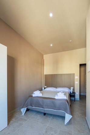 A modern hotel room with two beds, a bedside table, and a headboard with vertical lines.