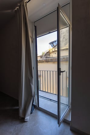 Una habitación con puerta de vidrio corredera que da a un balcón exterior.