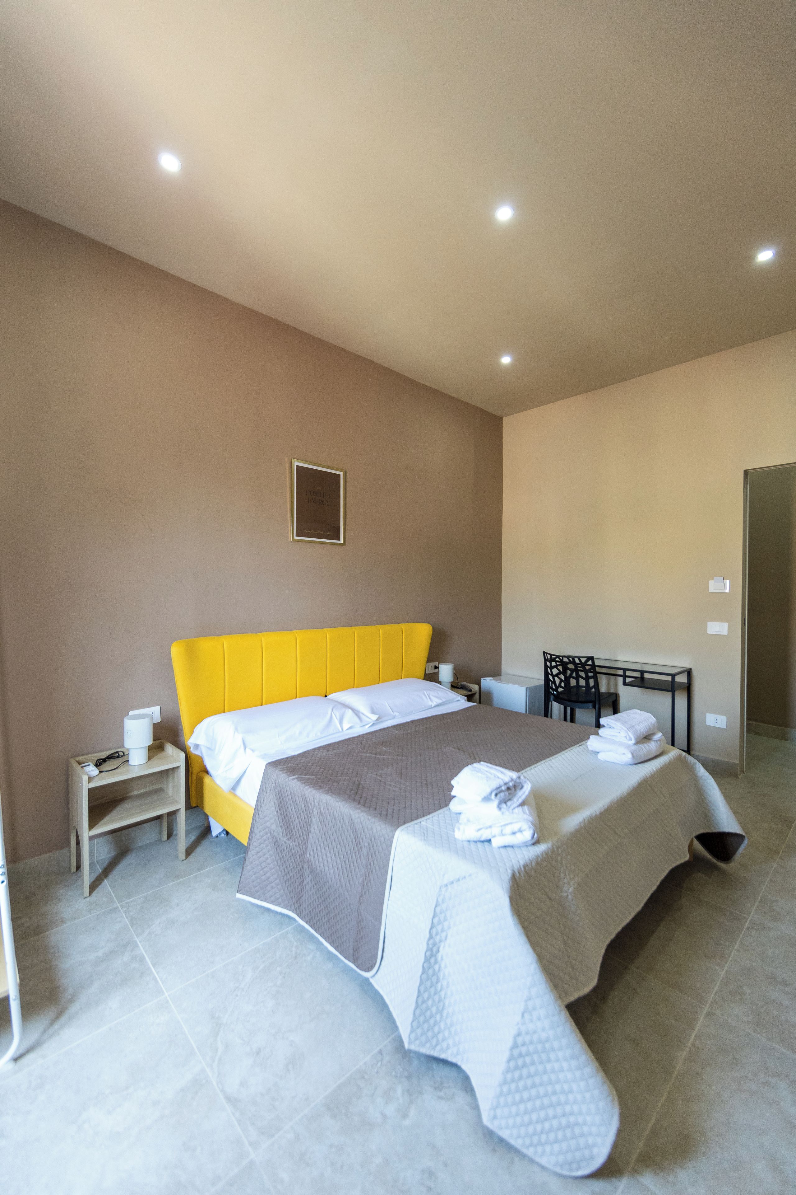 Ein Hotelzimmer mit Bett, Nachttisch und Schreibtisch mit Stuhl.