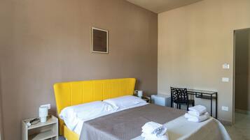 Ein Hotelzimmer mit Bett, Nachttisch und Schreibtisch mit Stuhl.