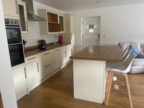 Eine moderne Küche mit weißen Schränken, einer Holz Arbeitsplatte und einem eingebauten Backofen.