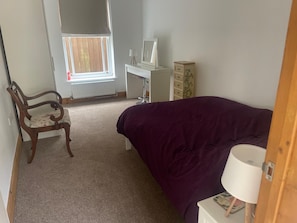 Ein Schlafzimmer mit Bett, Stuhl, Schreibtisch und Kommode.