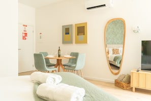 A hotel room with a bed, a round dining table with chairs, a large mirror, and a television. - Rosa Studio by Atlantic Holiday (Santa Cruz)