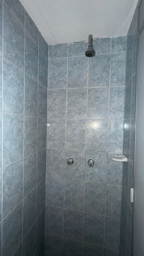 A shower stall with dark blue tiles, a showerhead, and two faucets. - HOSTAL HANOI (Bogotá)