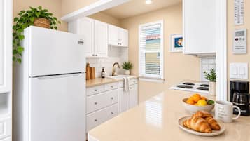 A modern kitchen with white cabinetry, a built-in oven, and a coffee maker on the counter.