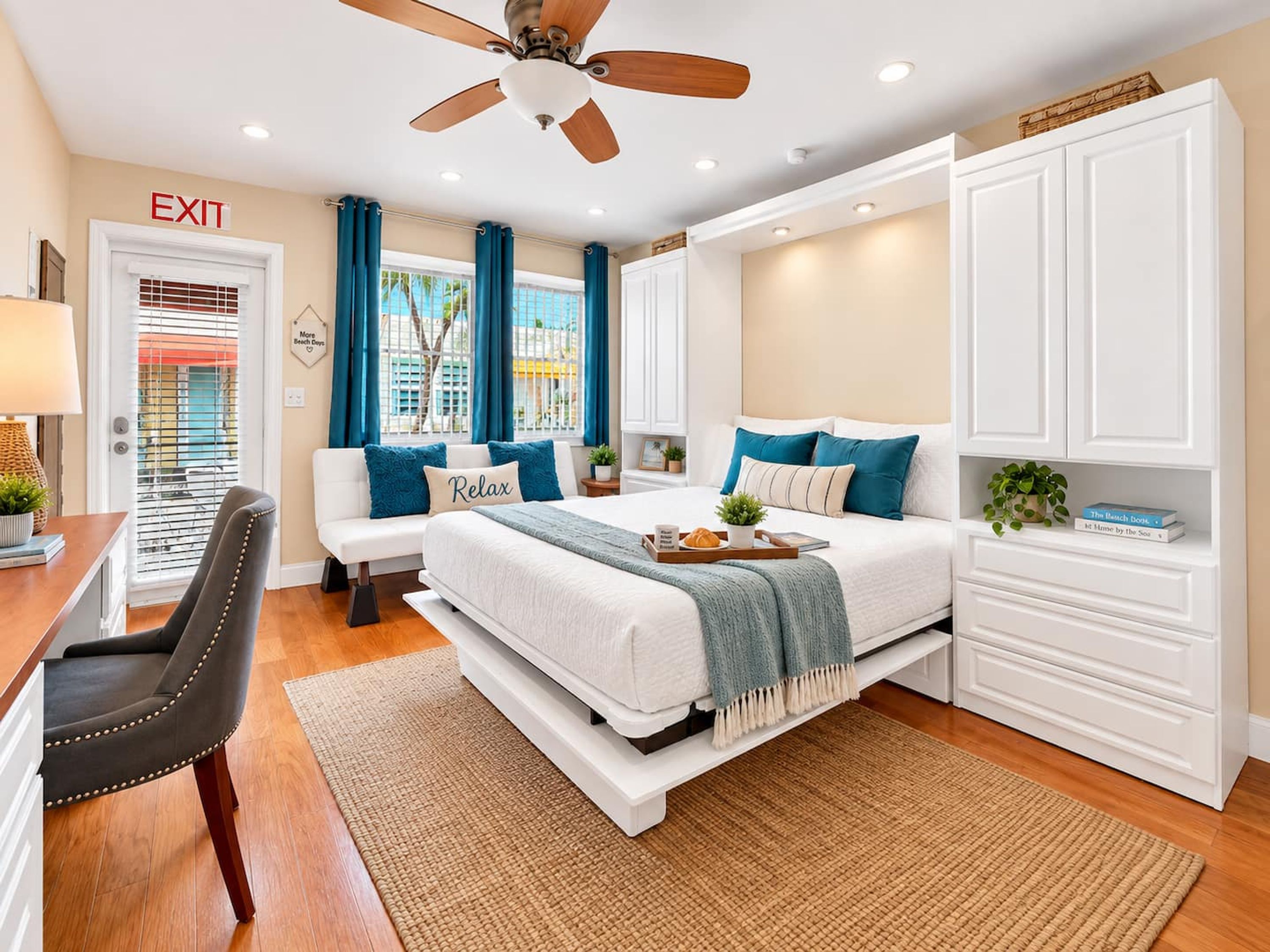 A bedroom with a bed, a desk, a chair, a wardrobe, and a ceiling fan.