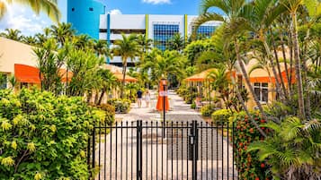 A gated entrance with a paved walkway leading to a building with a blue cylindrical structure and a modern design.