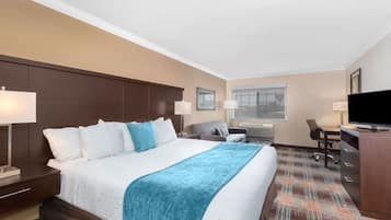 Ein Hotelzimmer mit einem großen Bett, einem Schreibtisch, einem Fernseher und einem Fenster.
