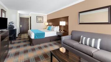 Une chambre d’hôtel comprenant un lit, un canapé, un bureau avec un ordinateur et une télévision.