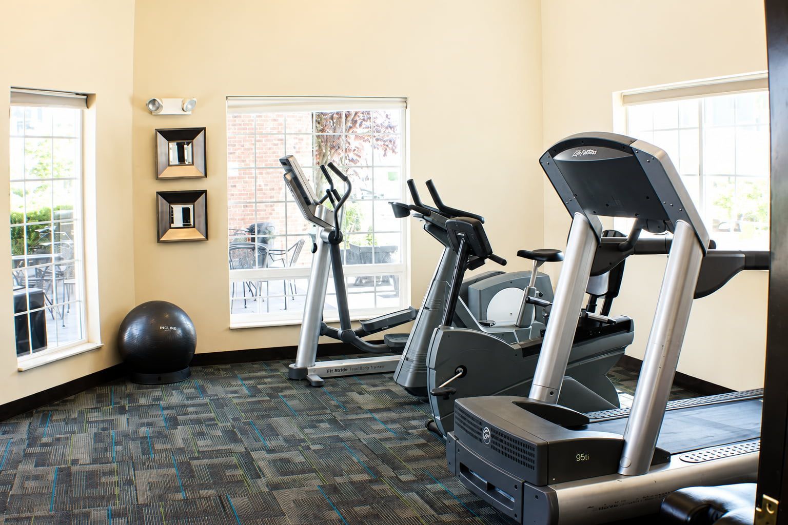 A fitness room with treadmills, an elliptical, and an exercise ball.