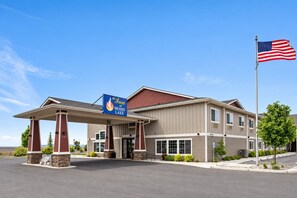 Un hotel con entrada cubierta, una bandera y un cartel que indica que es The Inn at Moses Lake.