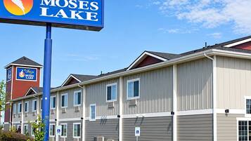 A hotel named 'The Inn at Moses Lake' with a signboard, a parking area with handicapped parking, and a building with multiple windows and a red tower.