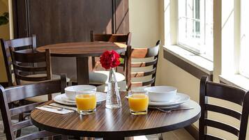 Un coin repas avec une table ronde, quatre chaises et un vase contenant une fleur rouge.