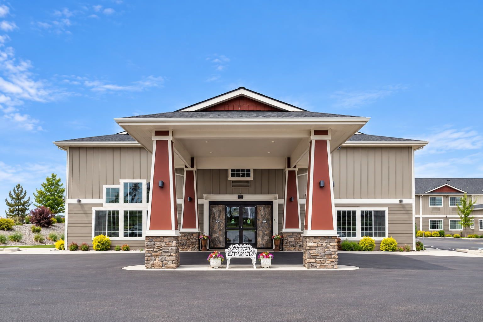 A two-story building with a stone facade, large windows, and a covered entrance area.