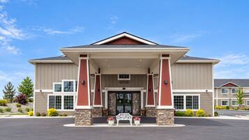 A two-story building with a stone facade, large windows, and a covered entrance area.