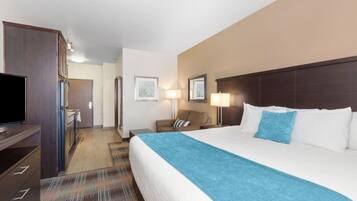 A hotel room with a large bed, a television, a desk, and a chair.