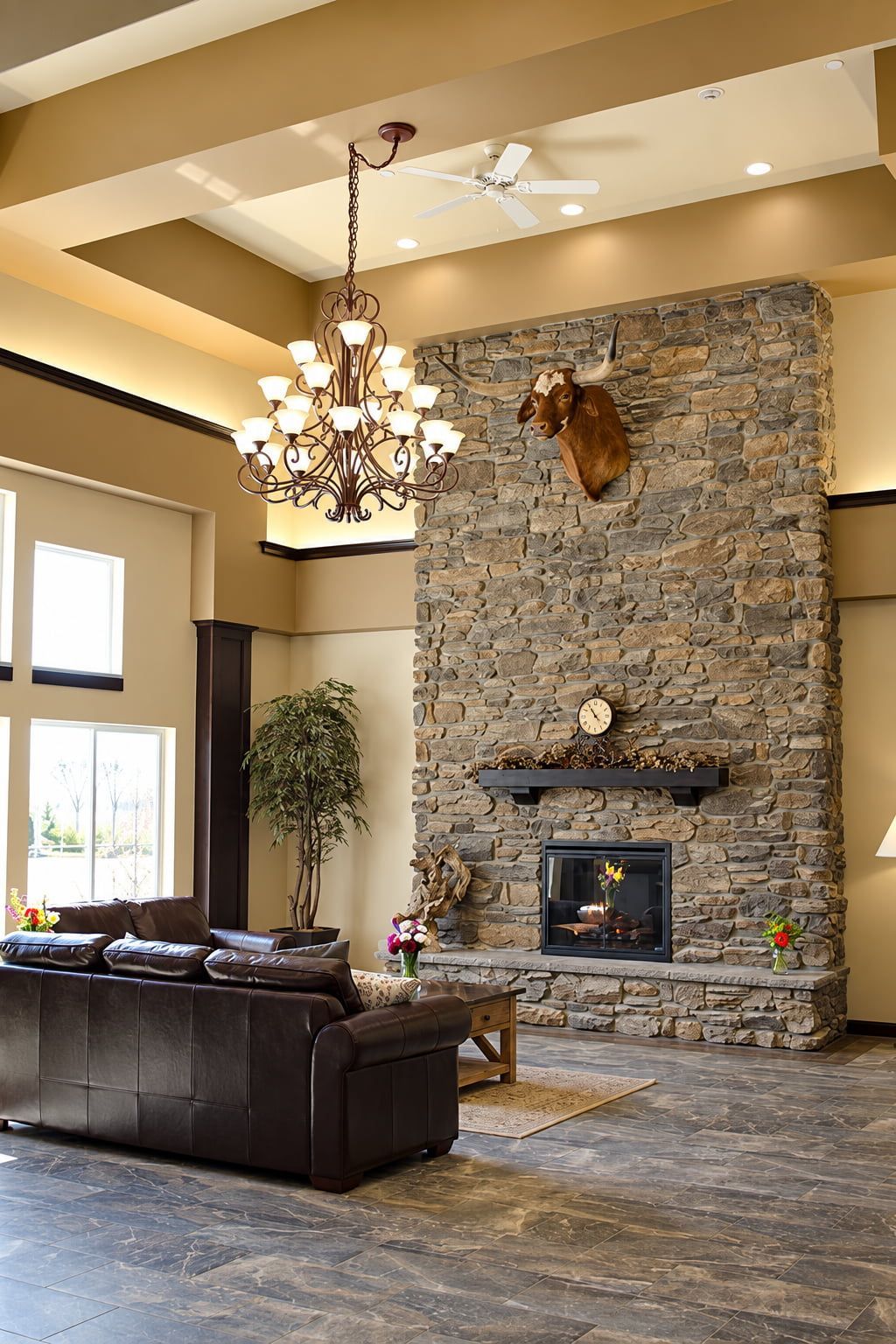 A spacious living room with a stone fireplace, a leather sofa, and a chandelier.