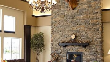 A spacious living room with a stone fireplace, a leather sofa, and a chandelier.