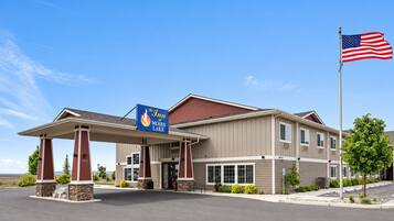 A hotel with a covered entrance, a flag, and a sign indicating it's The Inn at Moses Lake.