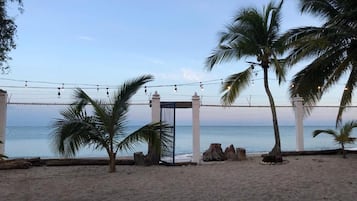 Una playa con una valla, palmeras y vistas al océano.