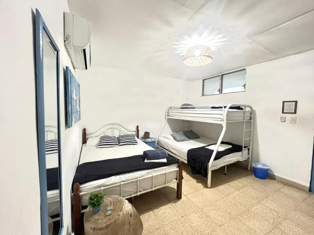 Una habitación con literas, una mesa redonda de madera, un espejo y una lámpara en el techo.