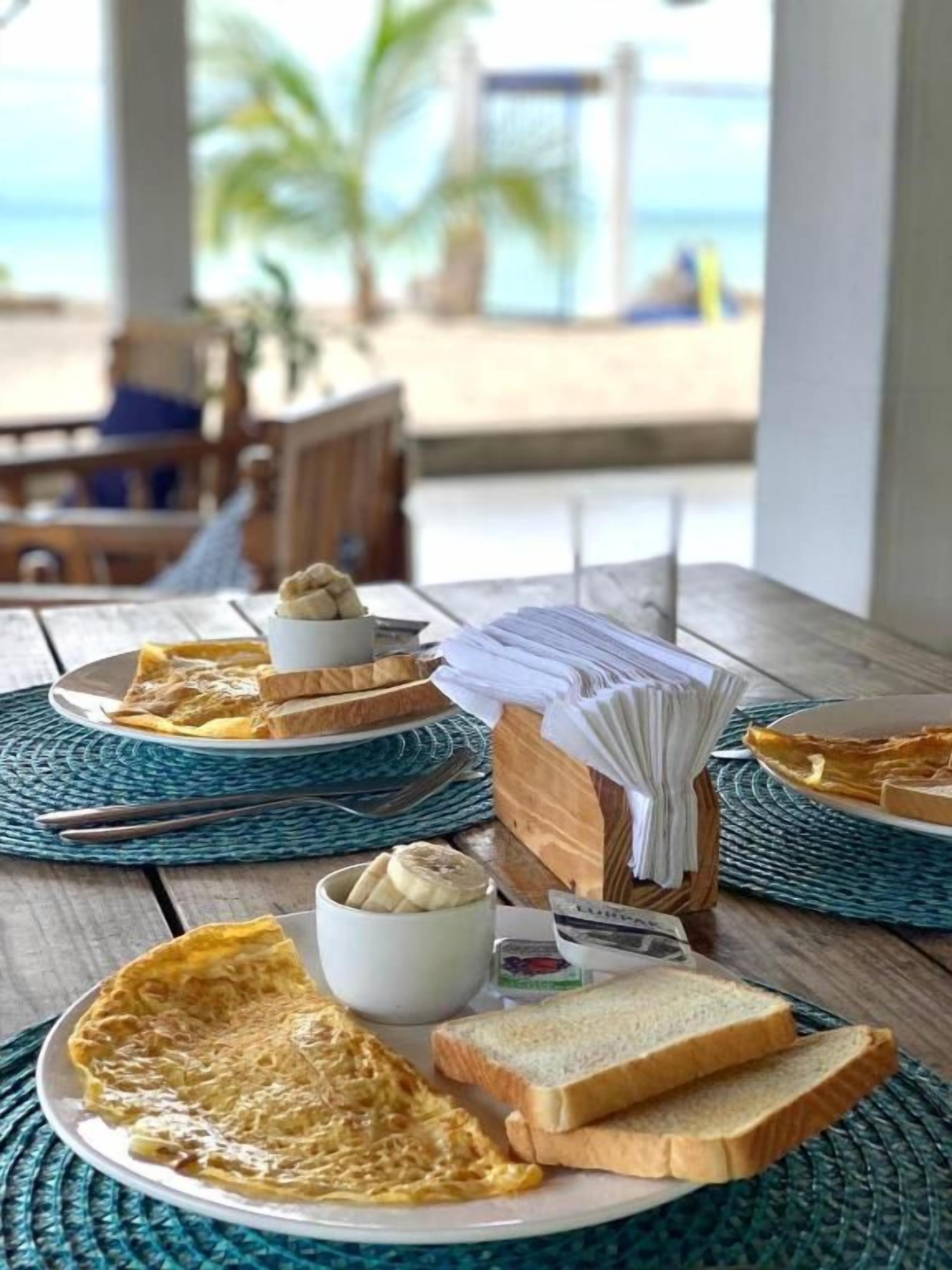 Desayuno con tostadas, huevos y una banana sobre una mesa de madera.