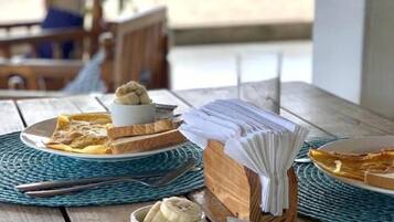Desayuno con tostadas, huevos y una banana sobre una mesa de madera.