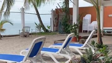A beachside lounge area with lounge chairs and potted plants.