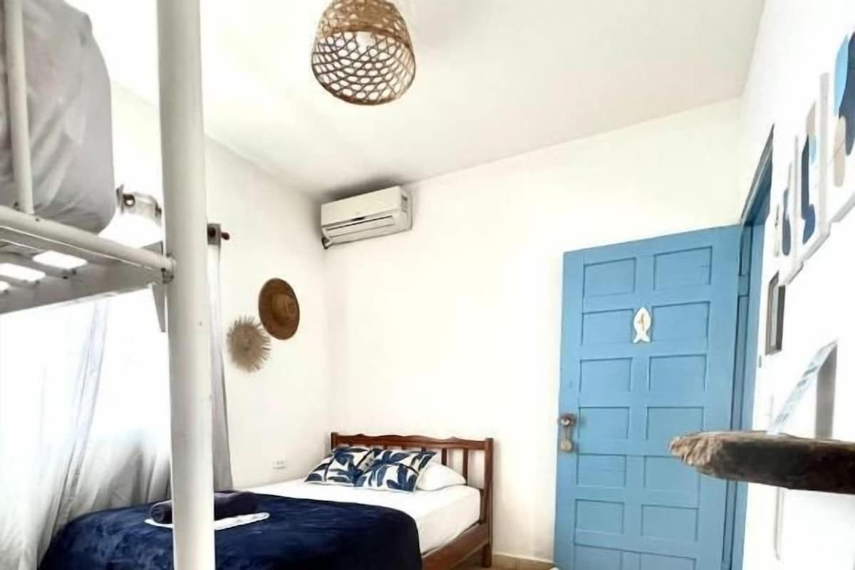 A bedroom with a bed, a wardrobe, a door, and a ceiling light fixture.