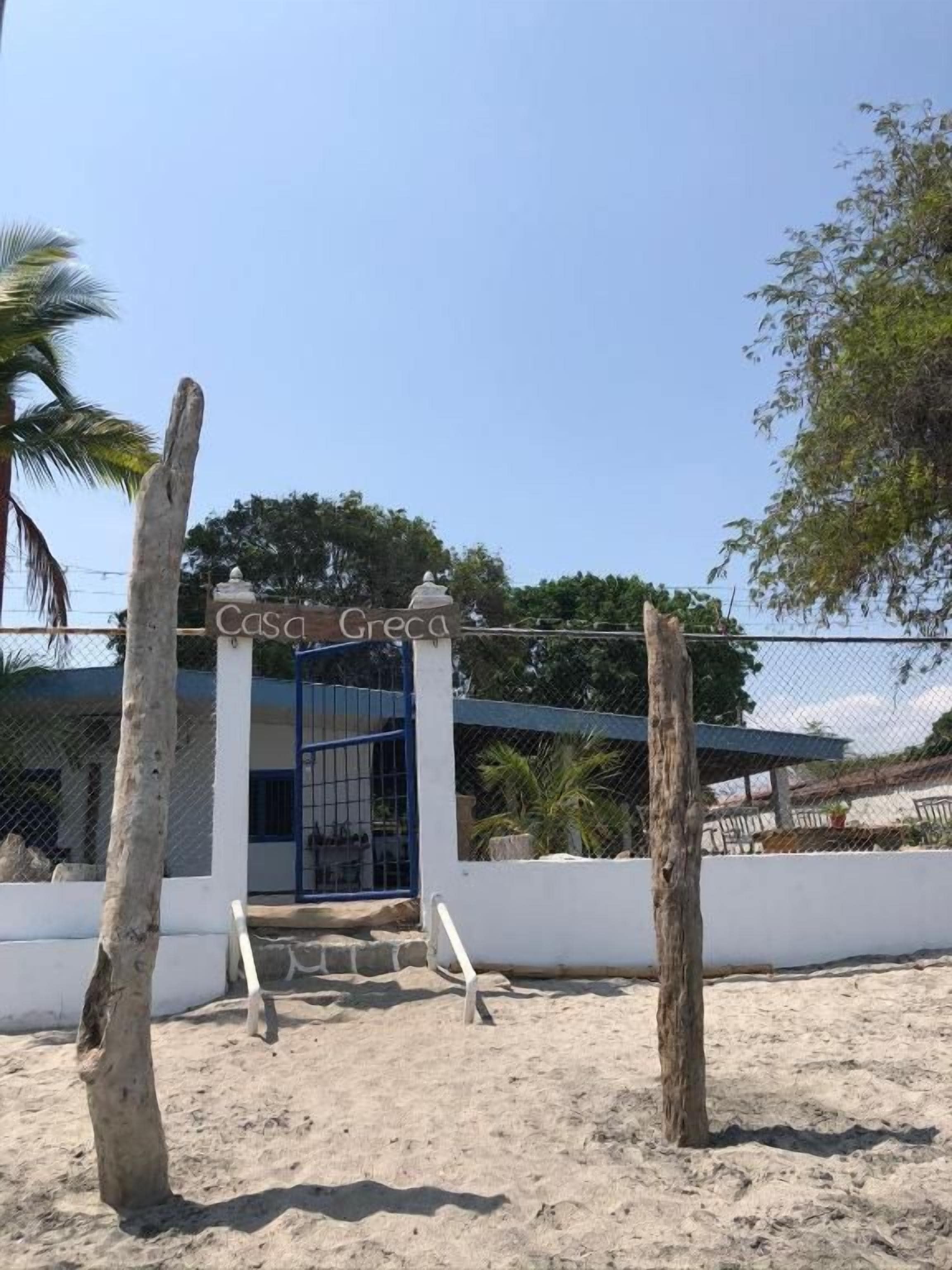 A gated entrance to a property named 'Casa Greca' with a clear sky above.