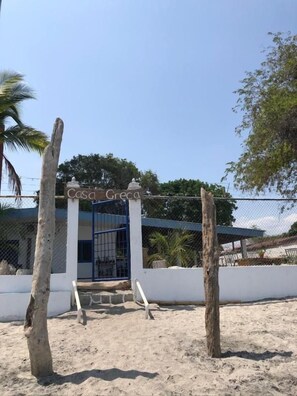 Una entrada protegida por un muro a una propiedad llamada 'Casa Greca', con cielo despejado.
