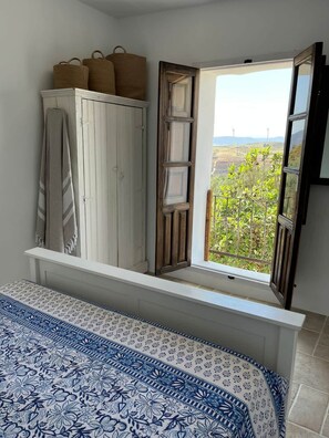 Ein Schlafzimmer mit Bett, Kleiderschrank, einem Fenster mit Blick auf Grünflächen und einem Balkon.
