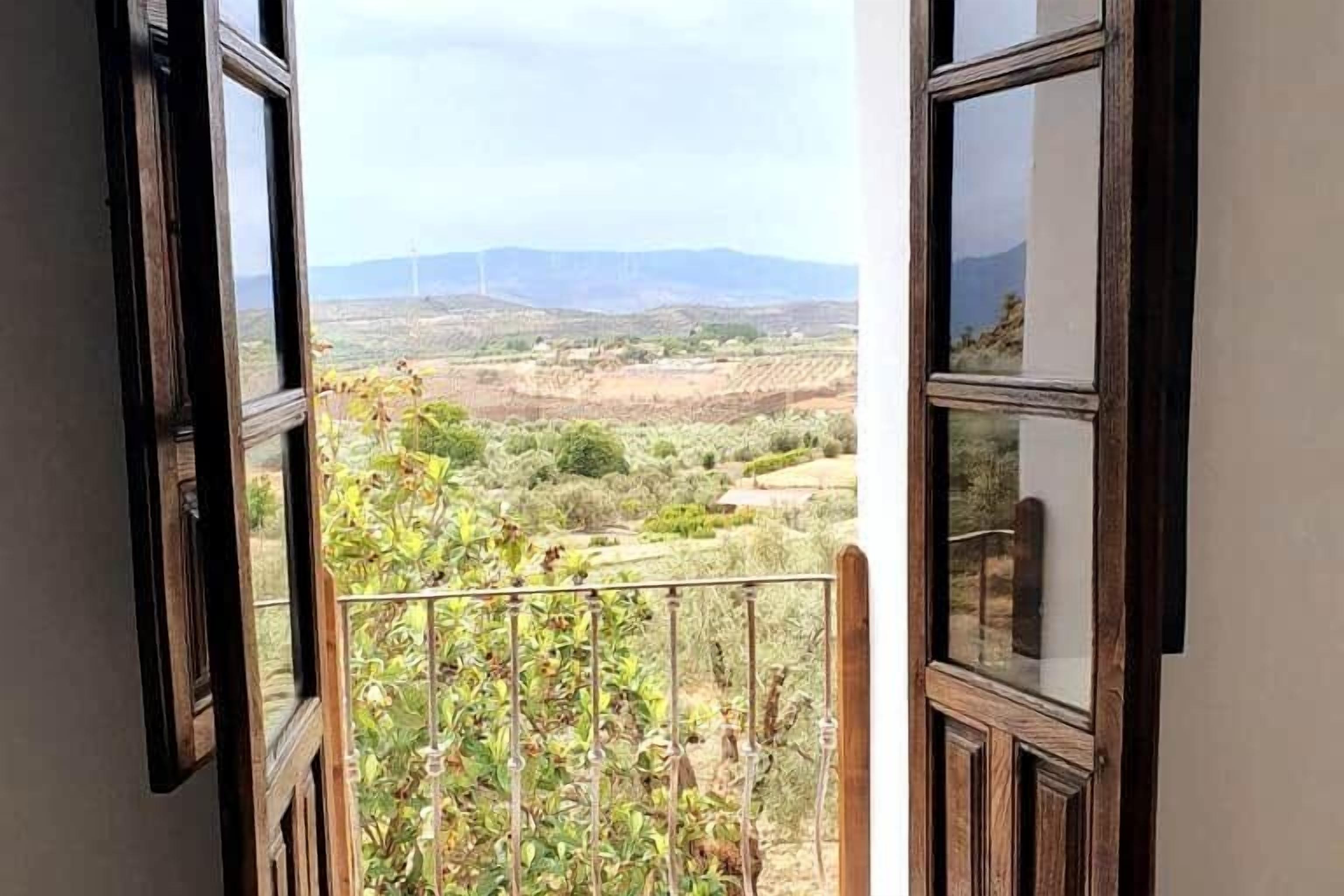Un balcon offrant une vue sur des collines lointaines et des éoliennes.