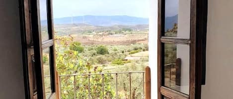 A balcony with a view of distant hills and wind turbines.