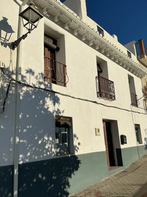 A building with a white facade, multiple windows, and balconies with metal railings. - Casa Blanca | Lecrin Valley, Granada (Acequias)