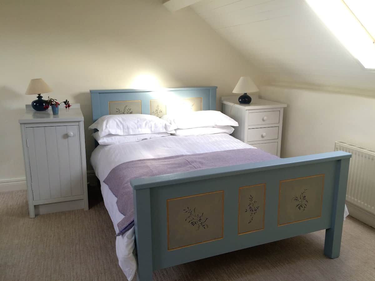Un dormitorio con una cama individual, una mesita de noche, un aparador y una ventana.
