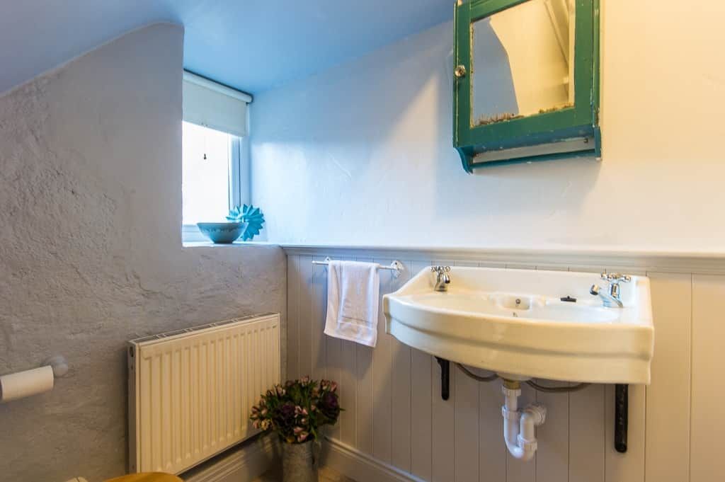 A bathroom with a white sink, a mirror, and a window with a view.