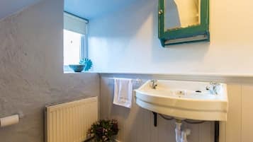 A bathroom with a white sink, a mirror, and a window with a view.