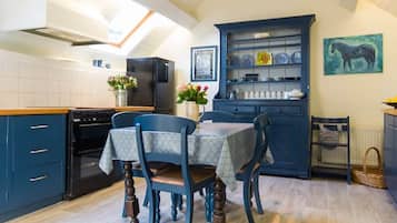 A kitchen with a dining table, chairs, a blue cabinet, and a painting on the wall.