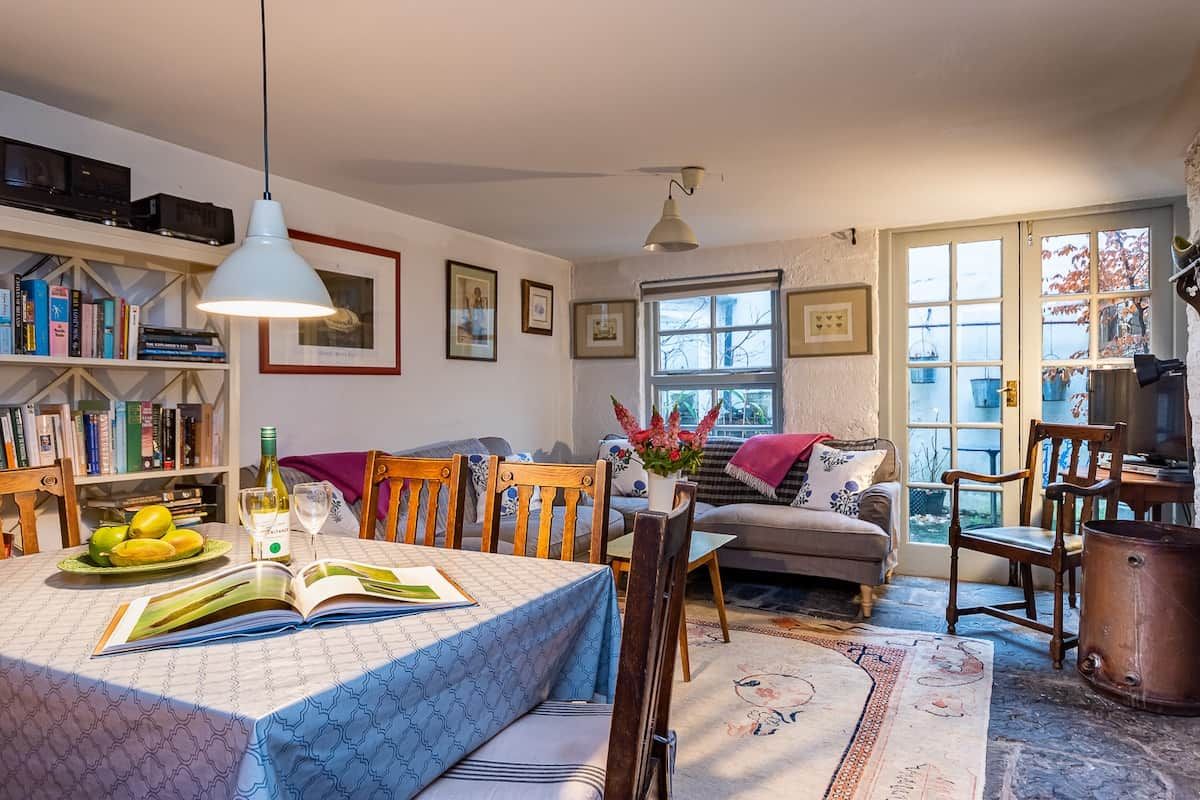 A cozy living room with a dining area, bookshelves, and a large window.
