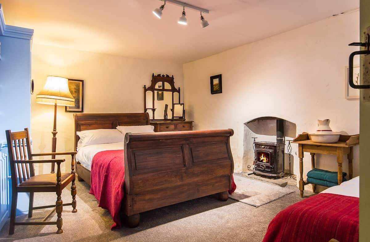Ein gemütliches Zimmer mit einem hölzernen Bett, einem Sessel, einer Lampe, einem Spiegel und einem Kamin.