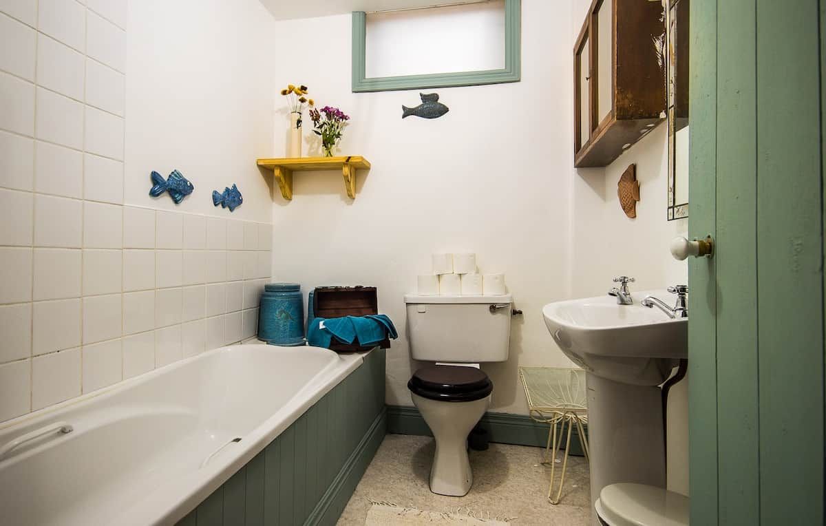 A bathroom with a bathtub, toilet, sink, and decorative fish wall art.