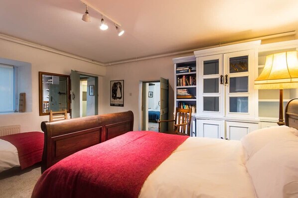 A bedroom with a large bed, a wardrobe, and a desk with a lamp. - Cleo Gallery basement Apartment (Kenmare)